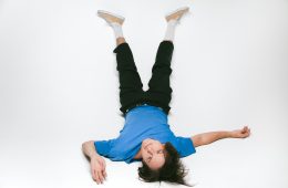 Whitmer Thomas lays on the floor looking upside down at the camera.