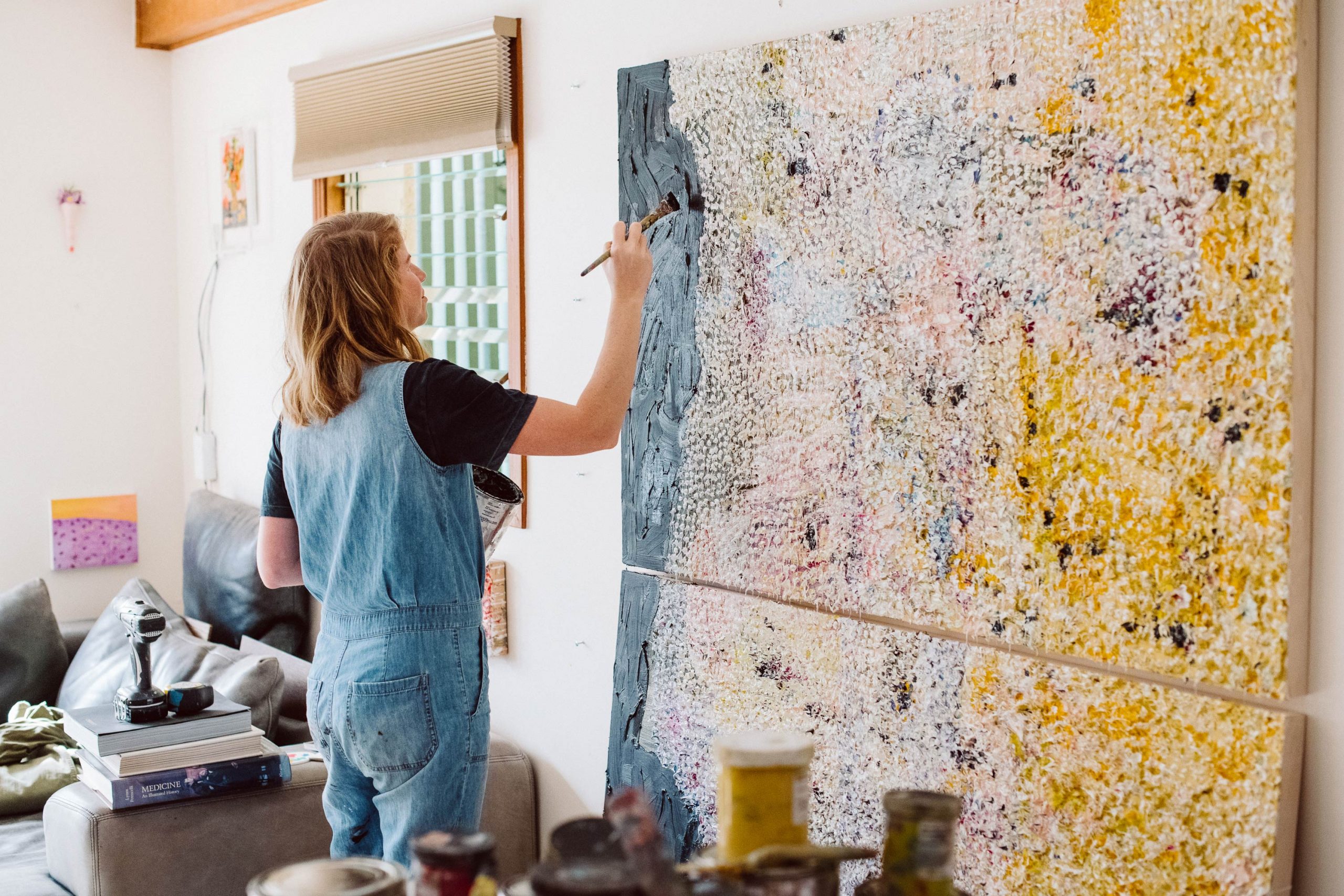 Vanessa Prager painting a large, multicolored canvas.