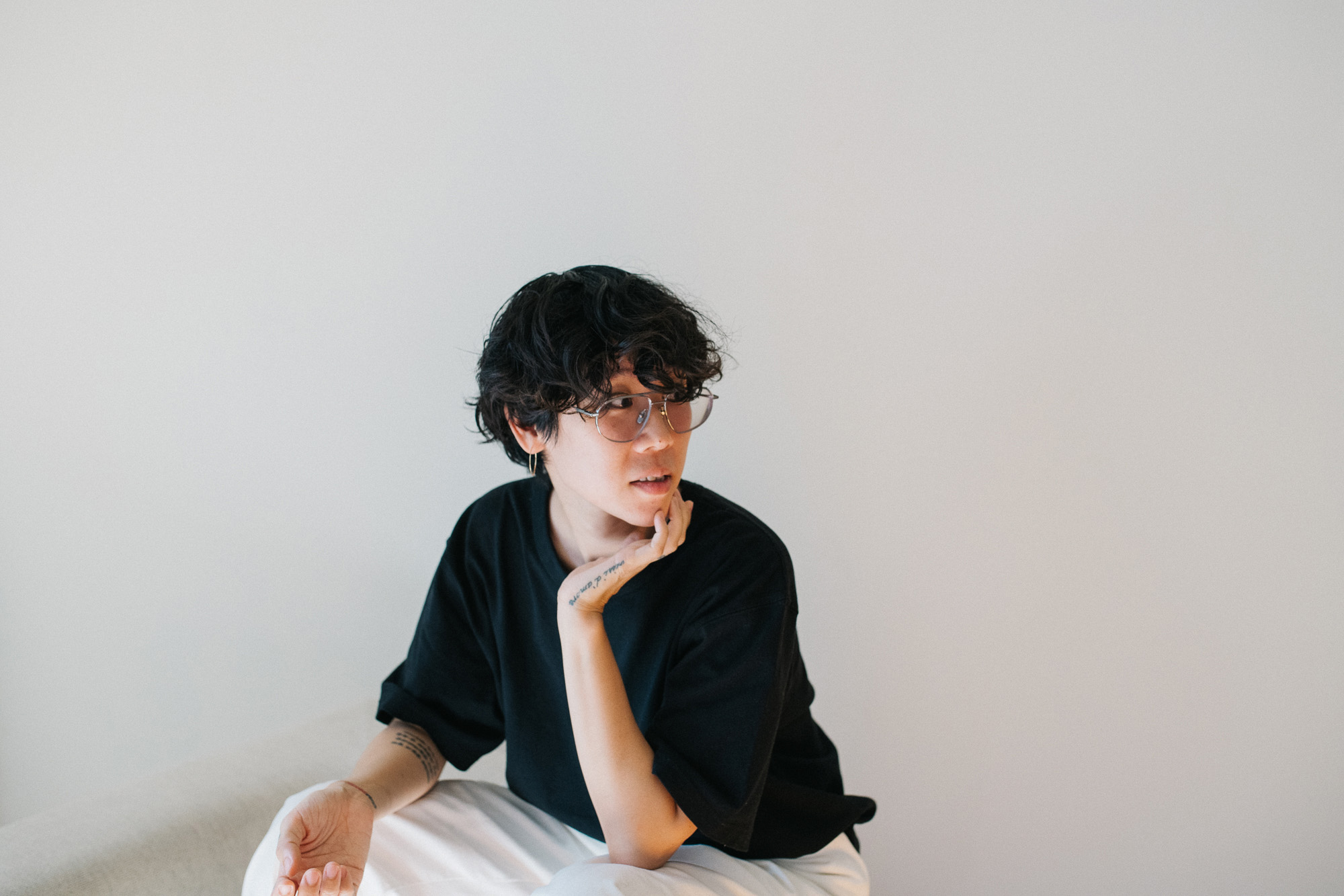 Michelle Jane Lee sitting against a white wall looking to her left.